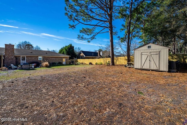 view of yard featuring a storage shed, an outdoor structure, and fence