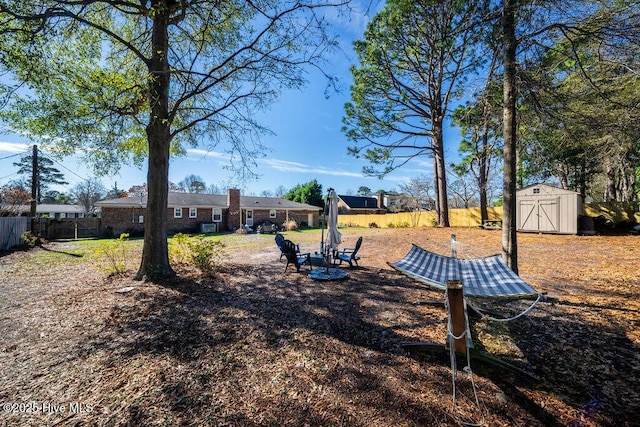 view of yard featuring fence, an outdoor structure, and a shed