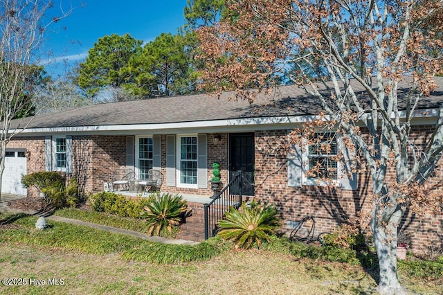 ranch-style home with a garage, brick siding, a porch, and roof with shingles