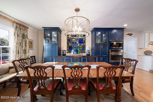 dining area with a chandelier, light wood-type flooring, ornamental molding, and recessed lighting