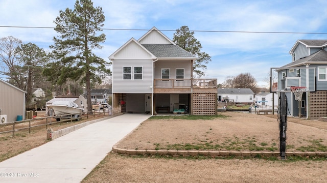 coastal home featuring a shingled roof, fence, stairway, concrete driveway, and a carport