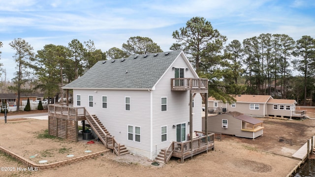 back of property featuring stairway, roof with shingles, and a wooden deck