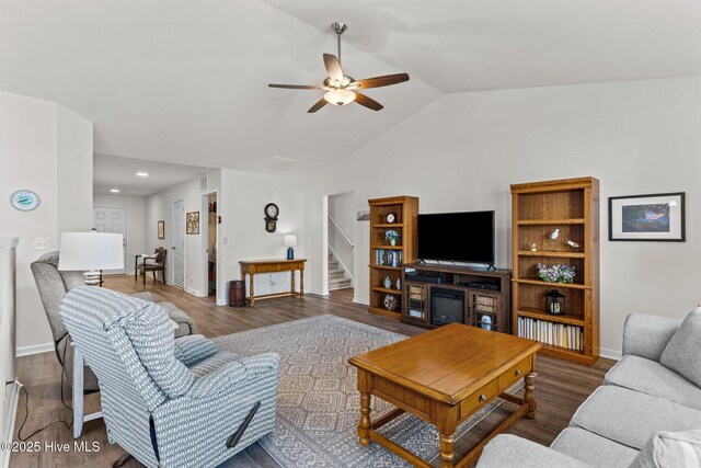 living room with ceiling fan, baseboards, wood finished floors, vaulted ceiling, and stairway