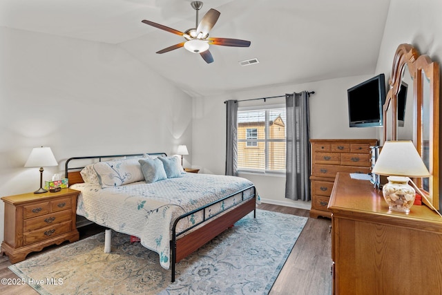bedroom with ceiling fan, visible vents, wood finished floors, and lofted ceiling