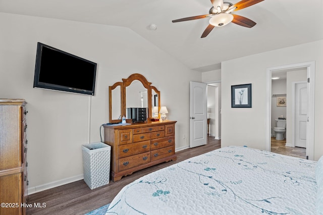 bedroom with baseboards, vaulted ceiling, ensuite bath, and wood finished floors