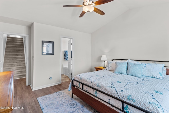 bedroom with ceiling fan, ensuite bath, baseboards, wood finished floors, and lofted ceiling