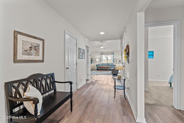 hall featuring baseboards, recessed lighting, and wood finished floors