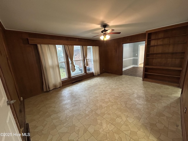 empty room with ceiling fan and wood walls