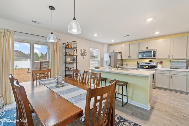 dining room with a healthy amount of sunlight, sink, and light hardwood / wood-style flooring