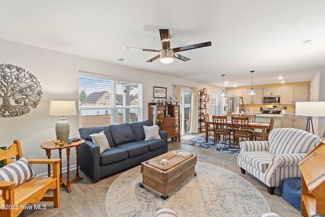 living room with ceiling fan and light hardwood / wood-style flooring