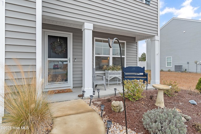 view of exterior entry with central AC and covered porch