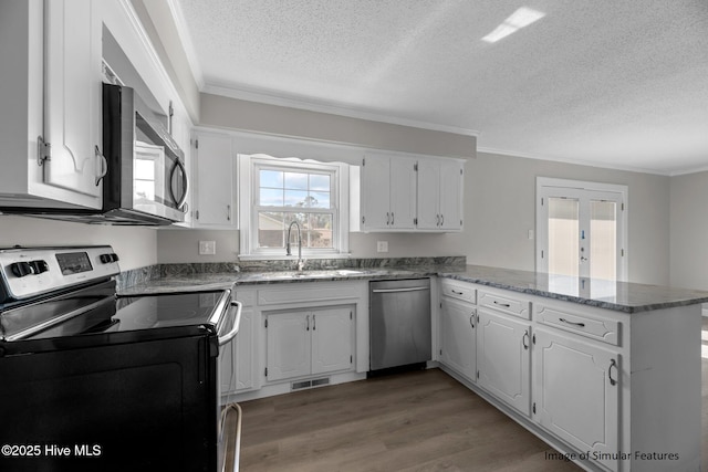 kitchen featuring appliances with stainless steel finishes, ornamental molding, white cabinetry, and kitchen peninsula