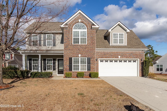 traditional-style home featuring brick siding, a shingled roof, an attached garage, driveway, and a front lawn