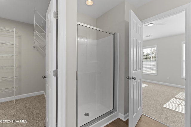 bathroom featuring a spacious closet, a shower stall, visible vents, and baseboards