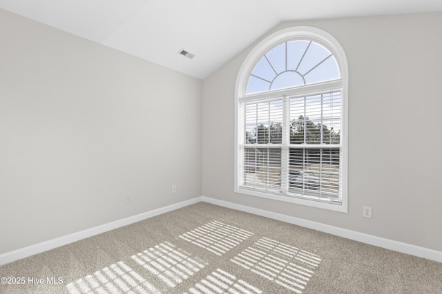 carpeted empty room featuring lofted ceiling, visible vents, and baseboards