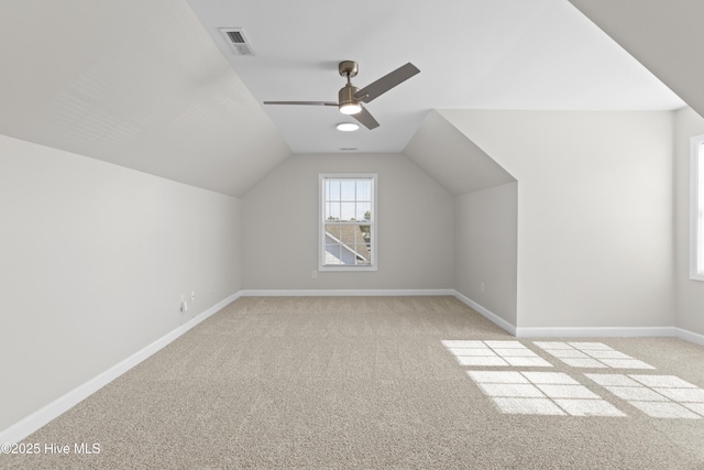 bonus room with light colored carpet, visible vents, a ceiling fan, vaulted ceiling, and baseboards