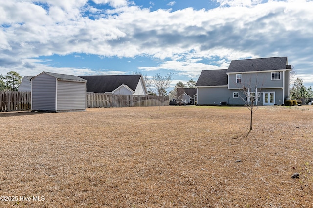 view of yard with an outbuilding, french doors, a storage unit, and fence