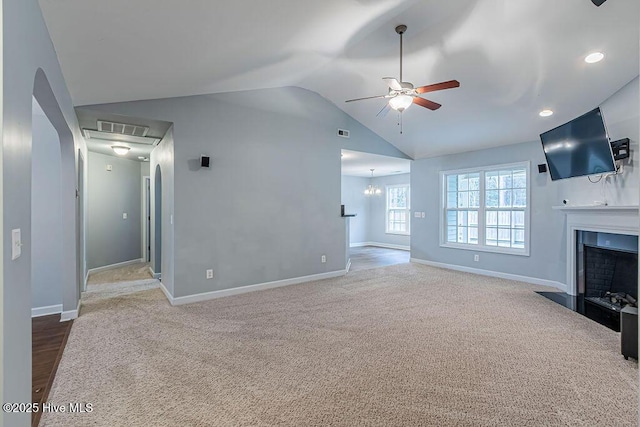 unfurnished living room featuring vaulted ceiling, ceiling fan with notable chandelier, and carpet