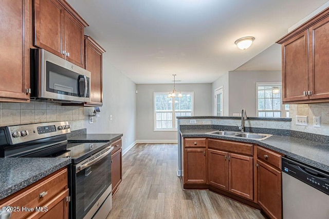 kitchen with light wood-type flooring, stainless steel appliances, sink, and a wealth of natural light