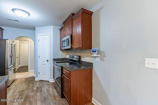 kitchen featuring hardwood / wood-style flooring, appliances with stainless steel finishes, and decorative backsplash