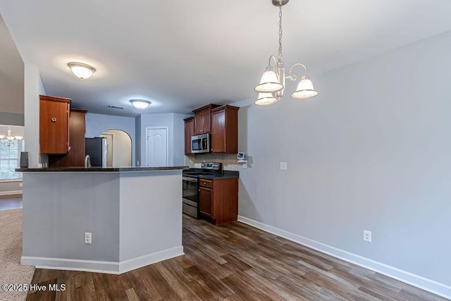 kitchen with tasteful backsplash, stainless steel appliances, decorative light fixtures, and a notable chandelier