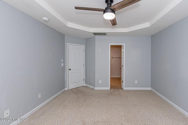 unfurnished bedroom with carpet, ceiling fan, and a tray ceiling