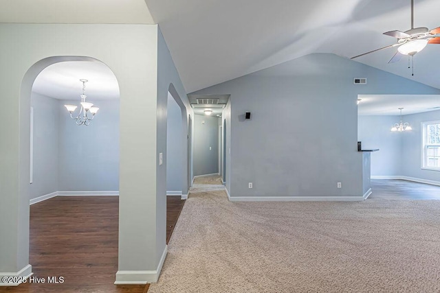 carpeted empty room with ceiling fan with notable chandelier and vaulted ceiling