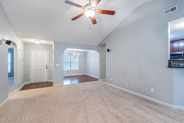 carpeted spare room with lofted ceiling and ceiling fan with notable chandelier