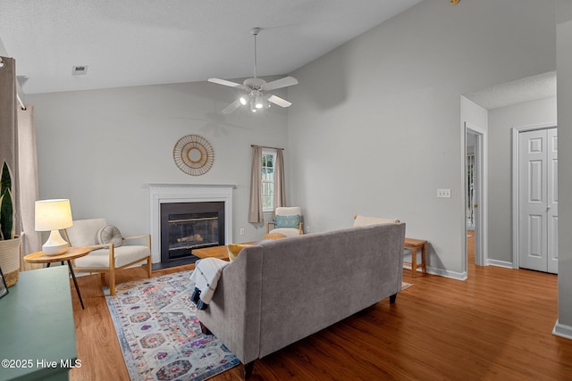 living room with ceiling fan, wood-type flooring, and vaulted ceiling