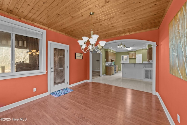 unfurnished dining area with a notable chandelier, arched walkways, light wood finished floors, baseboards, and wood ceiling