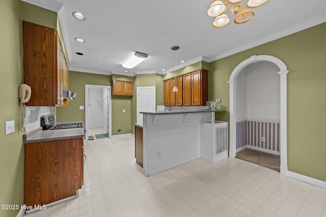 kitchen featuring a kitchen breakfast bar, a peninsula, exhaust hood, brown cabinetry, and crown molding