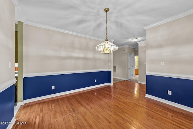 spare room featuring visible vents, crown molding, baseboards, and wood finished floors