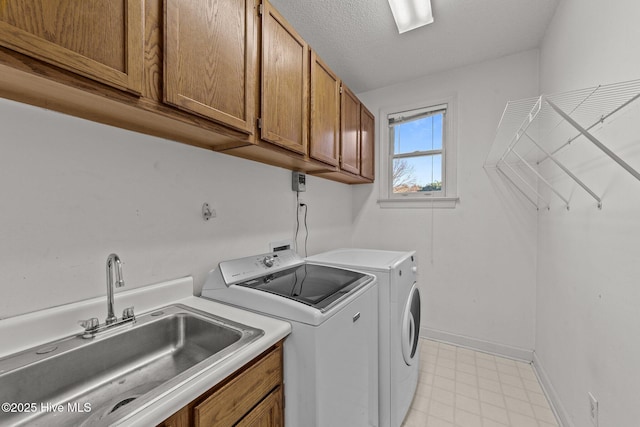 laundry room with light floors, baseboards, washing machine and clothes dryer, cabinet space, and a sink