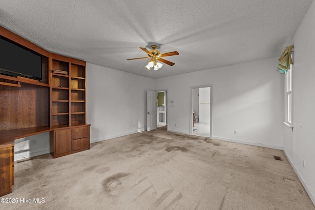 spare room featuring visible vents, a textured ceiling, carpet flooring, ceiling fan, and built in study area