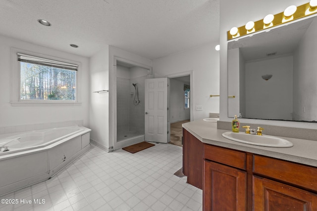 full bath featuring tile patterned floors, a garden tub, a stall shower, a textured ceiling, and vanity