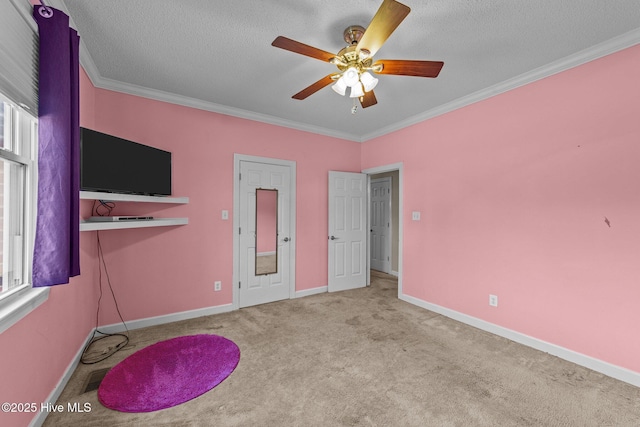 unfurnished bedroom with ornamental molding, a ceiling fan, a textured ceiling, carpet, and baseboards