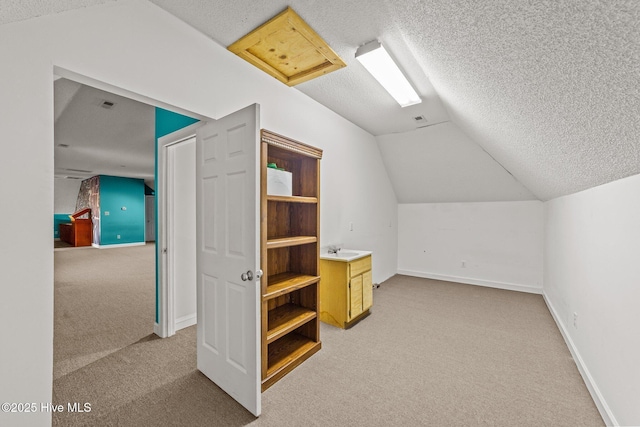 bonus room with baseboards, light colored carpet, vaulted ceiling, a textured ceiling, and a sink