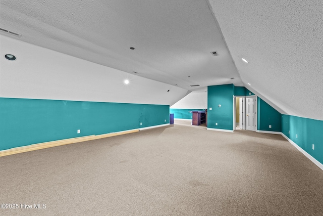 bonus room with visible vents, lofted ceiling, a textured ceiling, and carpet