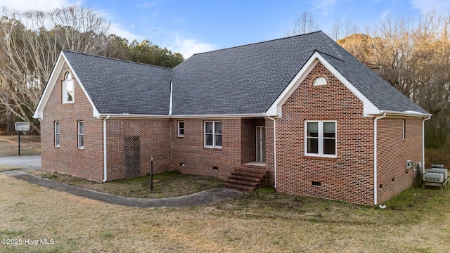 back of house with crawl space, a lawn, a shingled roof, and brick siding