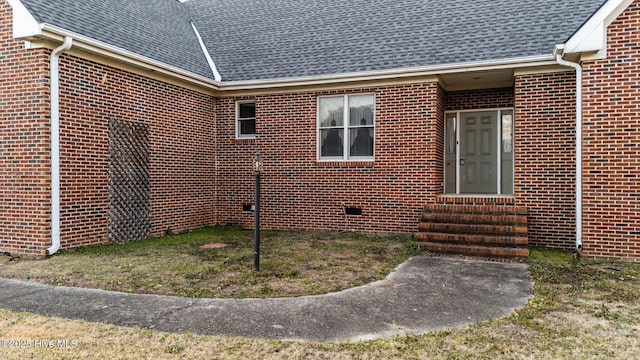 view of side of property featuring entry steps, brick siding, and roof with shingles