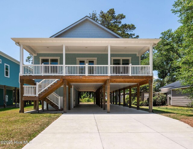 131 NW 18th St, Oak Island, NC 28465 - raised beach house featuring covered porch, a carport, concrete driveway, and a front lawn
