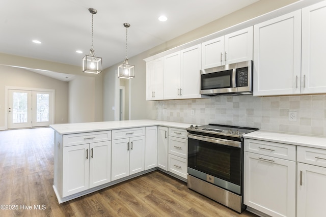 kitchen featuring white cabinetry, stainless steel appliances, kitchen peninsula, and hanging light fixtures