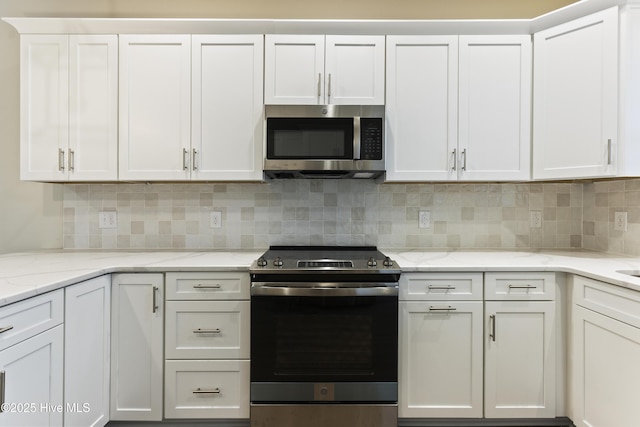 kitchen featuring tasteful backsplash, white cabinetry, appliances with stainless steel finishes, and light stone countertops