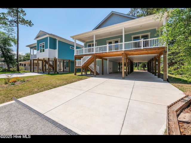 131 NW 18th St, Oak Island, NC 28465 - coastal inspired home with a porch, a carport, stairs, driveway, and a front lawn