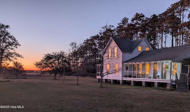 back of house at dusk featuring a yard