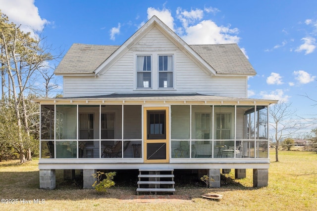 back of property featuring a lawn, roof with shingles, and a sunroom