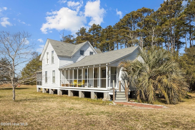 back of house featuring a yard, roof with shingles, and a sunroom