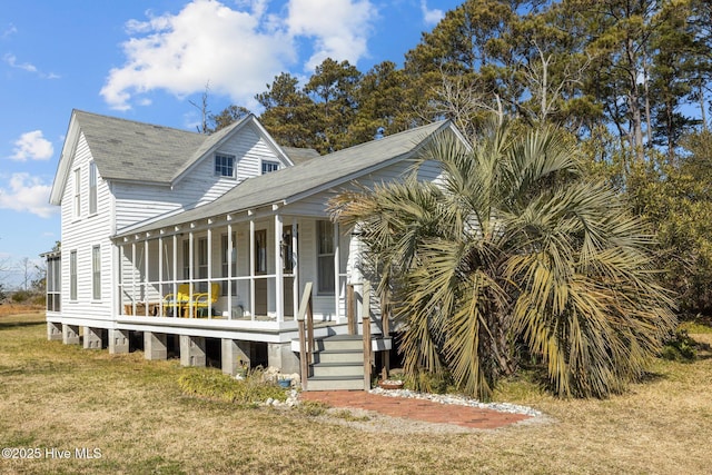 view of front of home featuring covered porch, a front lawn, and roof with shingles