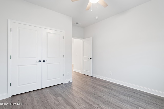 unfurnished bedroom with hardwood / wood-style flooring, a closet, and ceiling fan