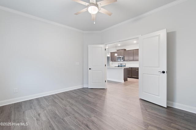 unfurnished living room with dark wood-type flooring, ornamental molding, and ceiling fan